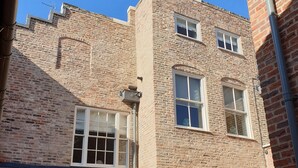 A brick building with multiple windows and doors, a visible chimney, and a clear blue sky. - 71 Micklegate - Apartment 1 (York)