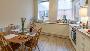 A modern kitchen with a dining table, chairs, and a window with a view of a brick building. - 71 Micklegate - Apartment 1 (York)