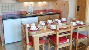 A compact kitchen with a microwave, coffee maker, sink, and a dining area with a table set for four.