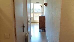A hallway with a radiator, a wooden cabinet, and a door leading to a balcony.