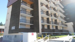 Un immeuble résidentiel à plusieurs étages, doté de balcons, avec une enseigne indiquant qu’il s’agit d’une résidence, et un ciel dégagé.
