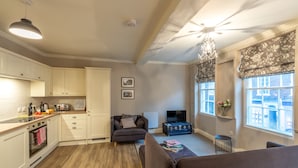 A modern kitchen with white cabinets and a wooden countertop, a grey sofa, and a chandelier. - 71 Micklegate - Apartment 3 (York)
