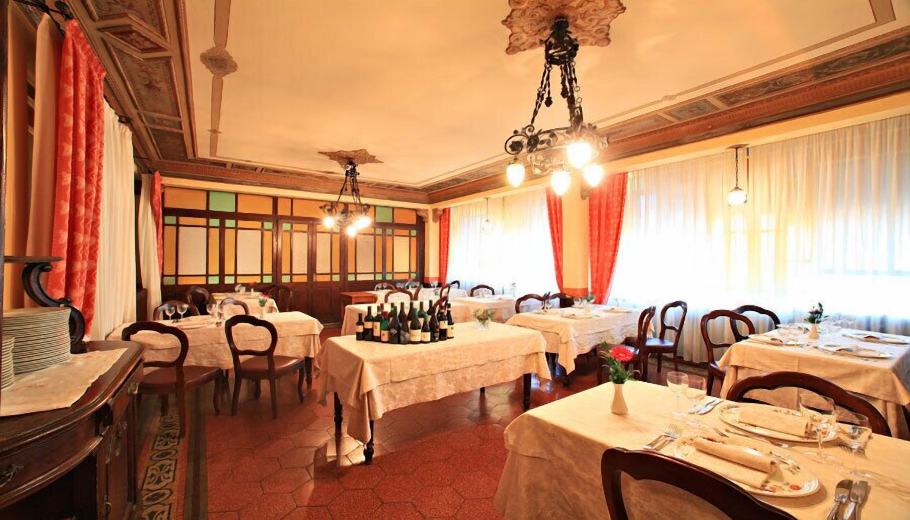 A dining area with multiple tables set for meals, a chandelier, and a view of the cityscape through large windows.