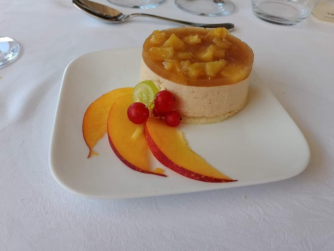 Un dessert su un piatto bianco, guarnito con frutta.