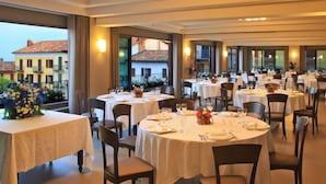 A restaurant with round tables, white tablecloths, and dark chairs. - Albergo Cannon D'Oro (Cocconato)