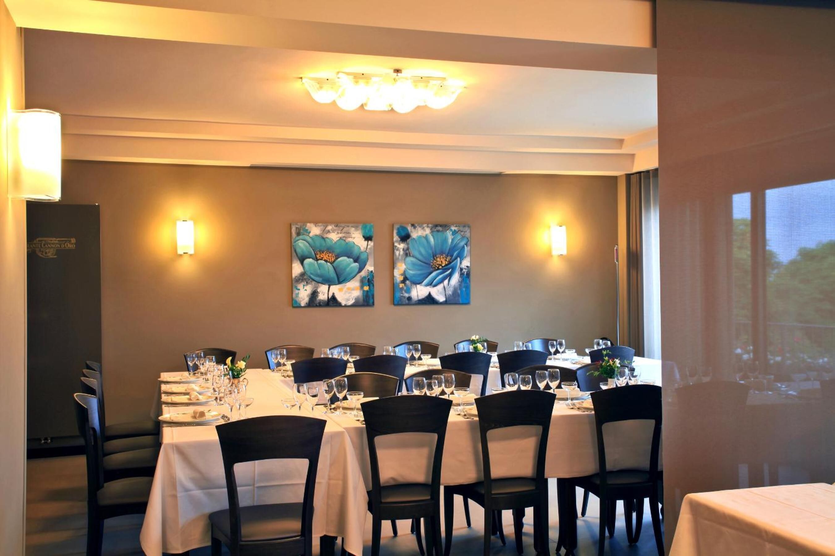 Zona de menjador amb taules preparades per a dinar, amb obra d'art a les parets i il·luminació ambiental.