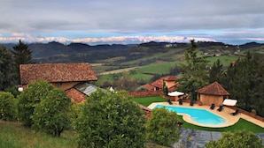 A villa with a swimming pool, surrounded by lush greenery and a mountainous backdrop. - Albergo Cannon D'Oro (Cocconato)