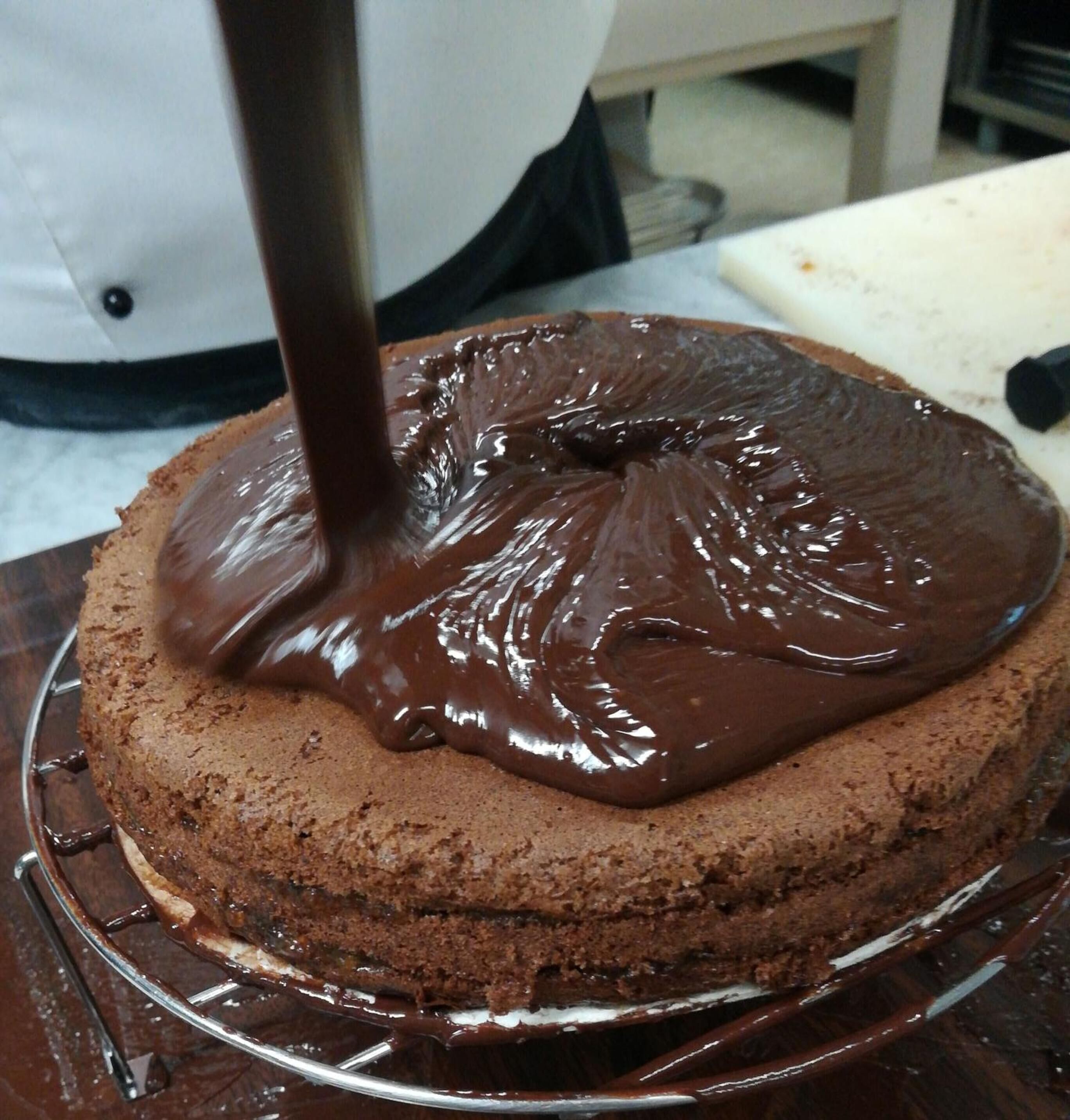 Una torta al cioccolato con una glassa lucida che viene versata sopra.