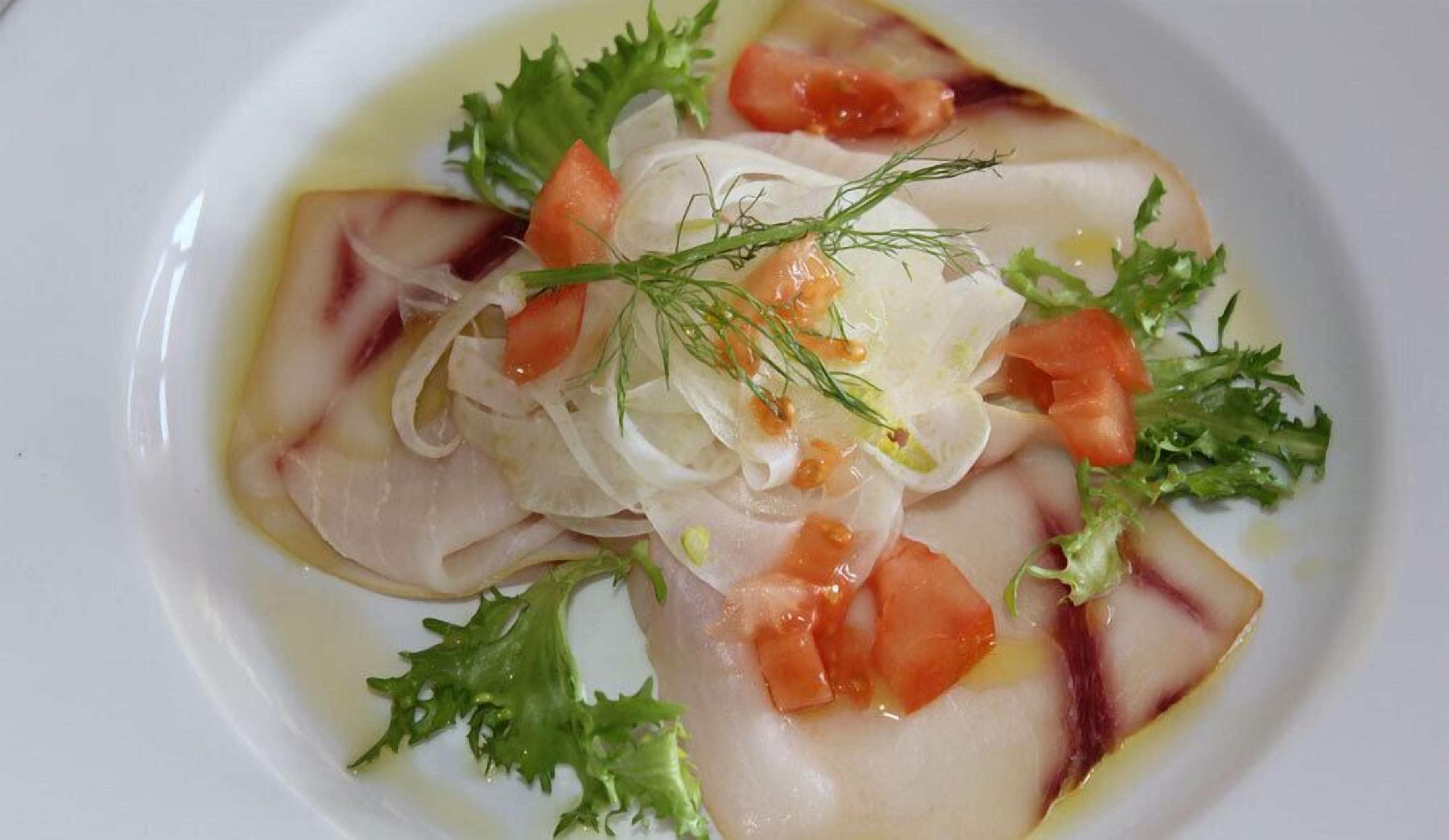 Ein Teller mit Fischfilet, Tomaten und Blattsalat.