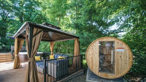 A wooden structure with a covered seating area and a sauna. - Hot Tub | New Build | Sauna | Game Room | Walk Downtown | Theater | Arcade (Ann Arbor)