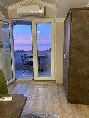 A room with a sliding glass door leading to an outdoor balcony with a view of the sea. - Su Residence (Trabzon)
