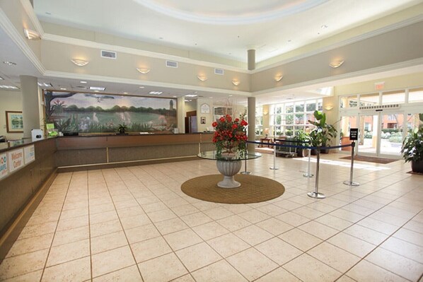 A spacious lobby with a reception desk, a large painting, and a central floral arrangement. - NEW in South Florida (Weston)