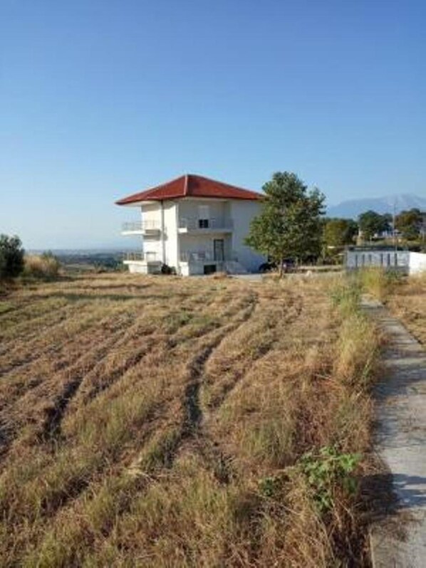 A two-story building with a red roof, situated on a hillside with a clear view of the landscape.