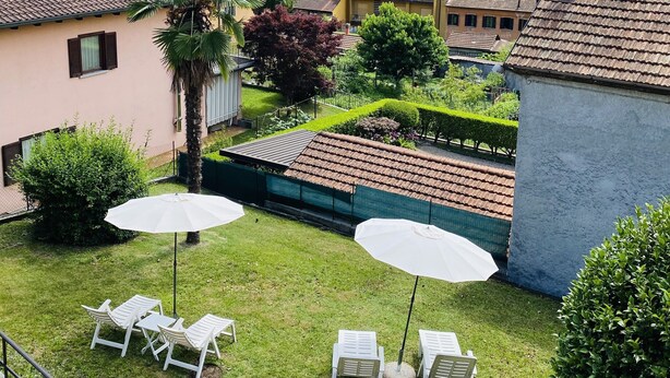 Zona residencial con vistas a un lago, una torre del reloj y un jardín bien cuidado con mobiliario exterior.