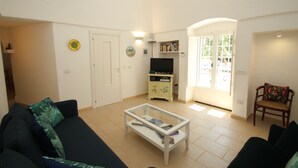 A living room with a sofa, a coffee table, a television, and a bookshelf. - Authentic Trullo & Villa with Pool – Perfect for Families & Groups (Ceglie Messapica)