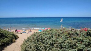 Una playa con gente, sombrillas y una bandera.