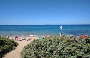 Una spiaggia con persone, ombrelloni e una bandiera.