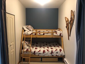 Uma cama beliche com escada, uma porta e uma parede com objetos decorativos.