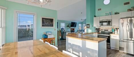 A modern kitchen with a central island, white cabinetry, and stainless steel appliances.