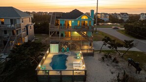 Una casa de dos pisos con piscina y zona de estar al aire libre.