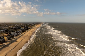 Een kustgezicht met strand, zee en een rij huizen langs de kust.