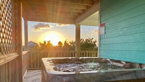 Un jacuzzi en una terraza de madera con vista al atardecer.