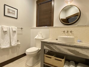 Ein Badezimmer mit Toilette, Waschbecken mit Spiegel und einem gerahmten Bild an der Wand.