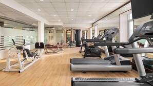Un gimnasio con cintas de correr, máquinas de pesas y un espejo grande.