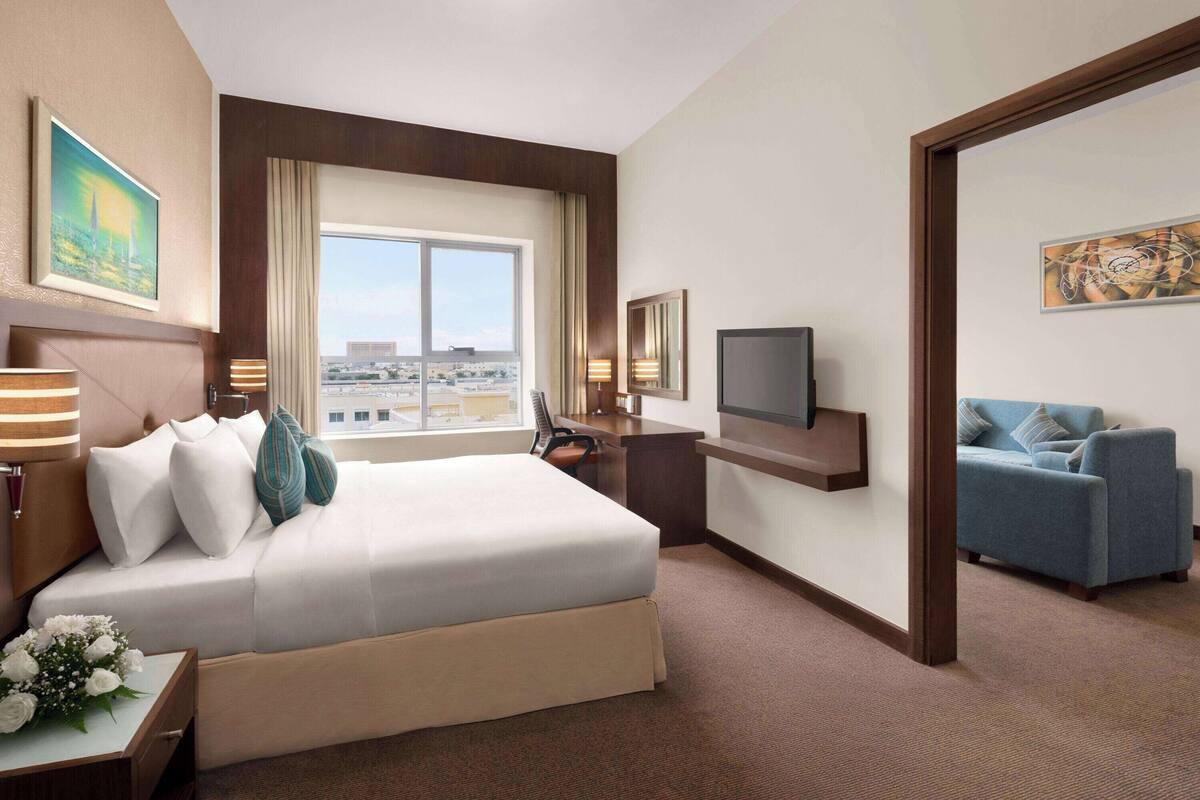A hotel room with a large bed, a desk, a television, and a sofa.