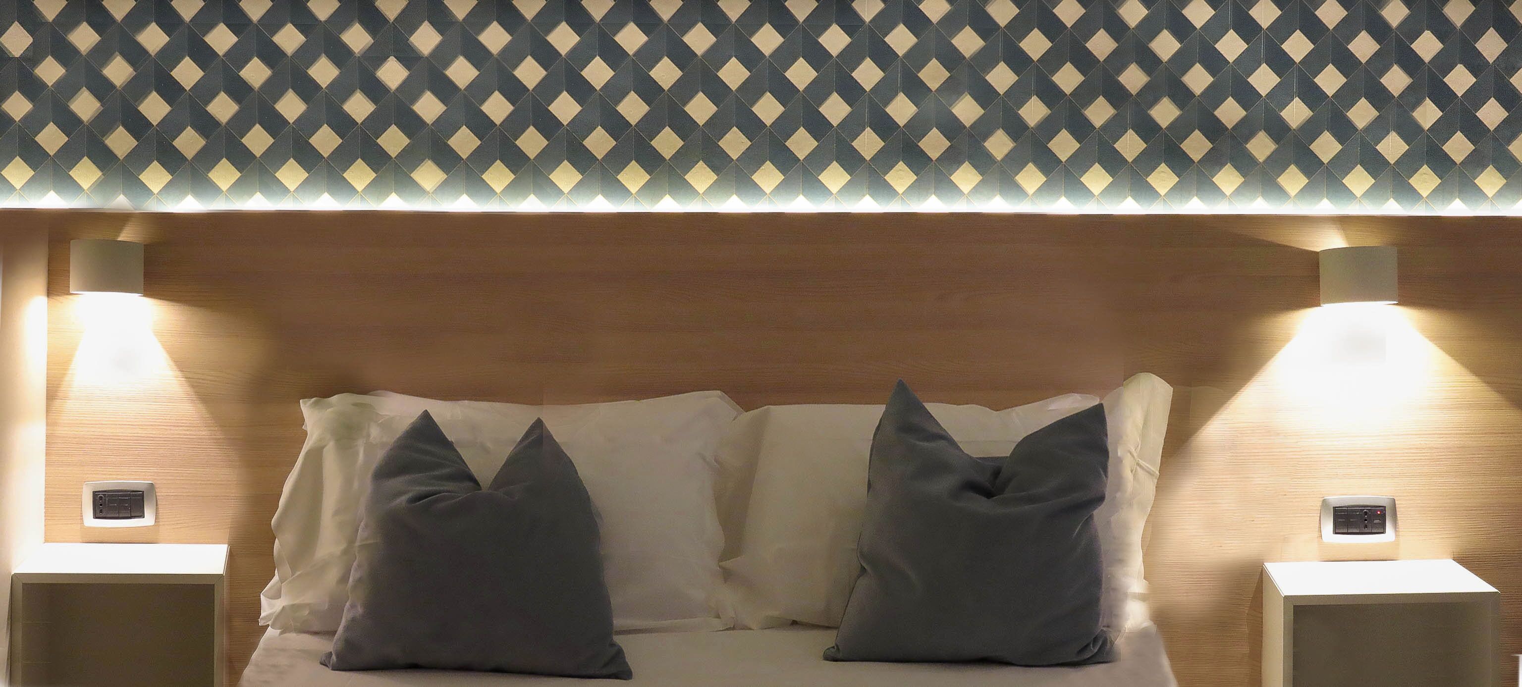A neatly made bed with two pillows and a wooden headboard. There are two bedside tables with lamps on either side.