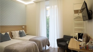 A hotel room with two beds, a desk, a chair, a TV, and a window with curtains. - My Maison 109 (Rome)