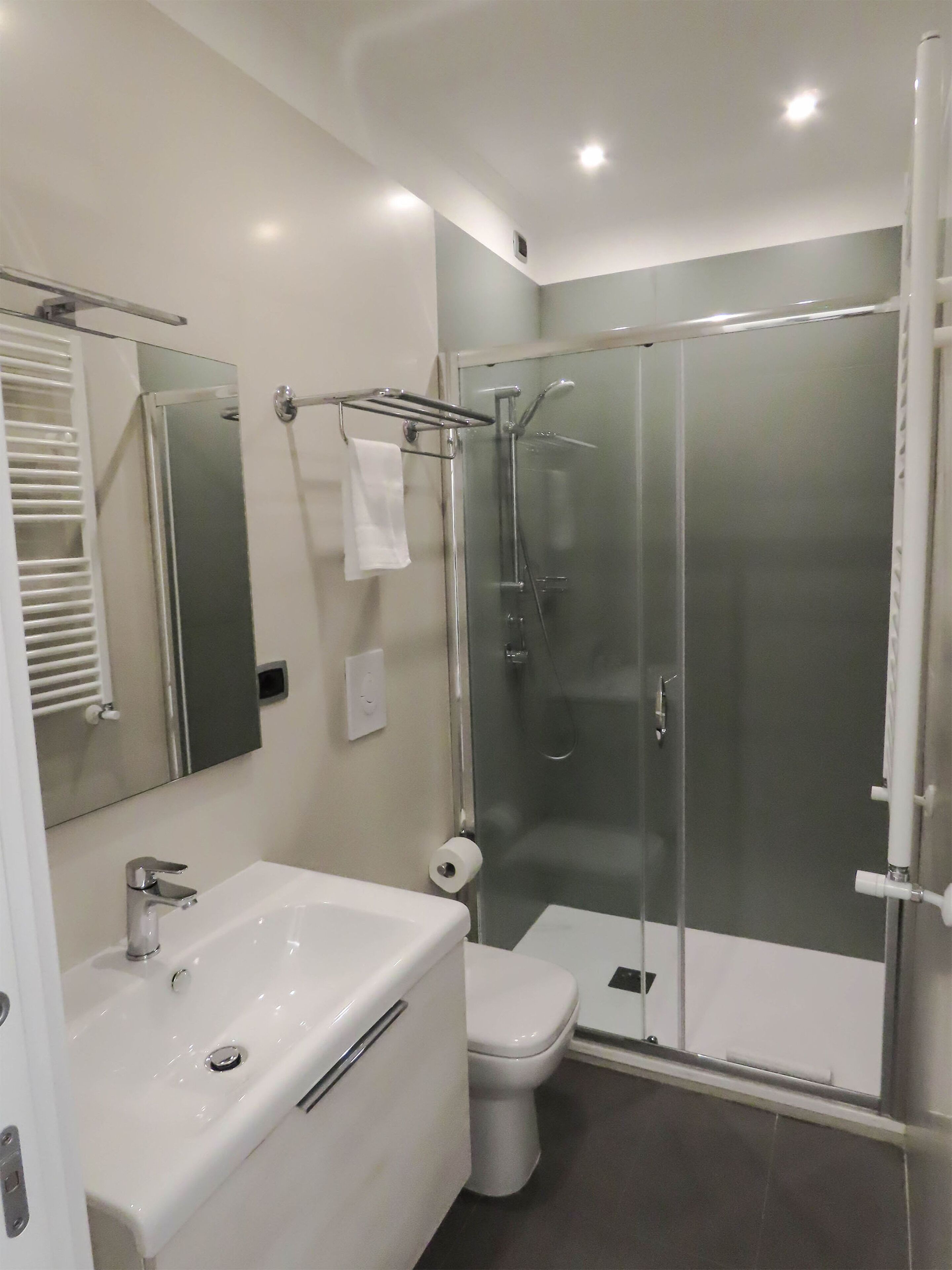 A modern bathroom with a white sink, toilet, and glass-enclosed shower.