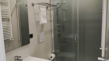 A modern bathroom with a white sink, toilet, and glass-enclosed shower.