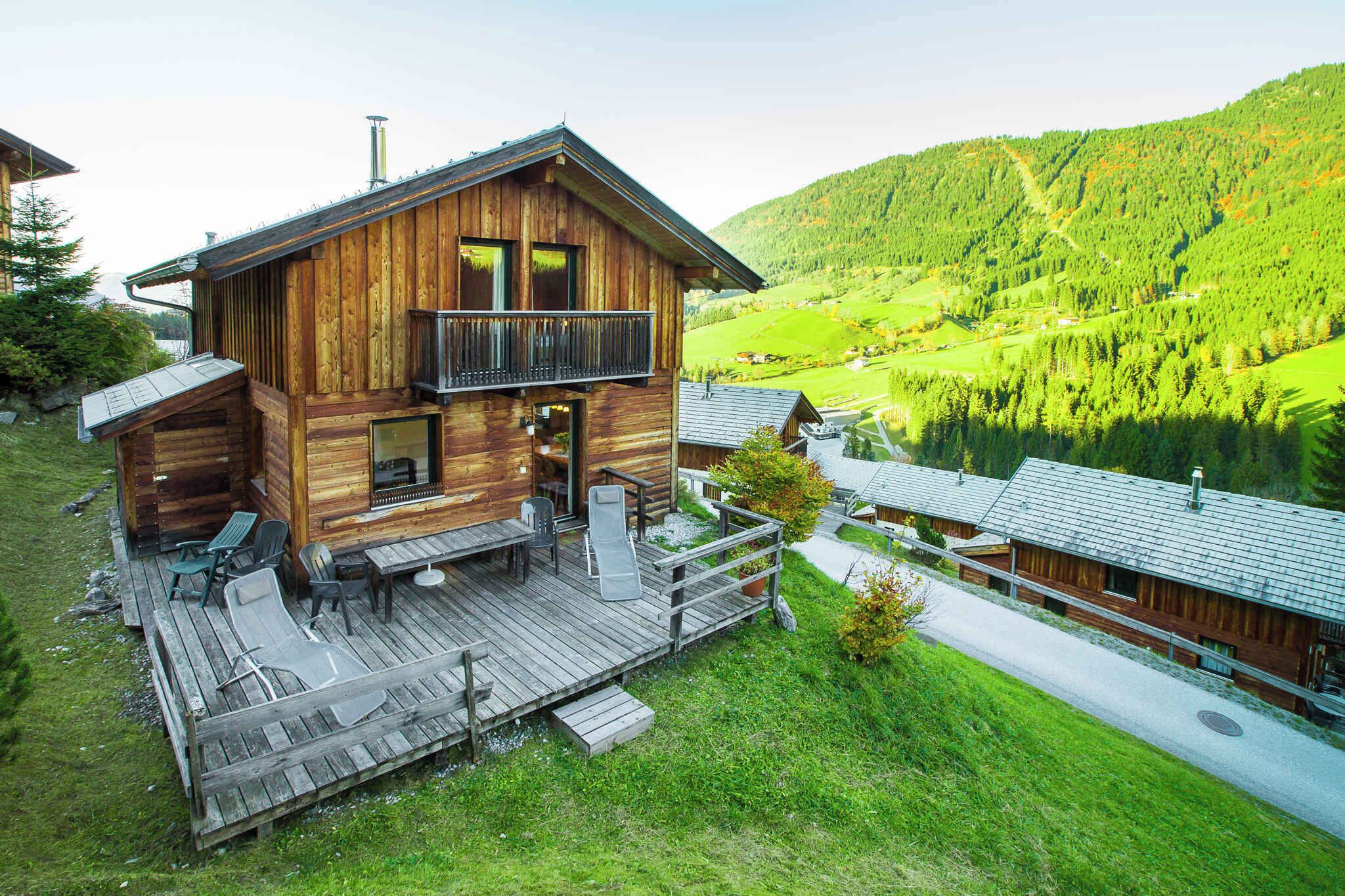 Een houten chalet met balkon, terras en een zitgedeelte buiten.