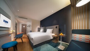 A modern hotel room with a large bed, a desk, a chair, and a small table with fruit. - Holiday Inn Express Shanghai Huijin by IHG (Shanghai)