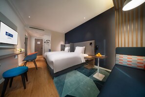 A modern hotel room with a large bed, a desk, a chair, and a small table with fruit. - Holiday Inn Express Shanghai Huijin by IHG (Shanghai)
