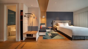 A modern hotel room with a bed, bedside table, seating area, and a view of the bathroom. - Holiday Inn Express Shanghai Huijin by IHG (Shanghai)