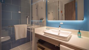 A modern bathroom with a glass shower enclosure, a white sink, and a large mirror. - Holiday Inn Express Shanghai Huijin by IHG (Shanghai)