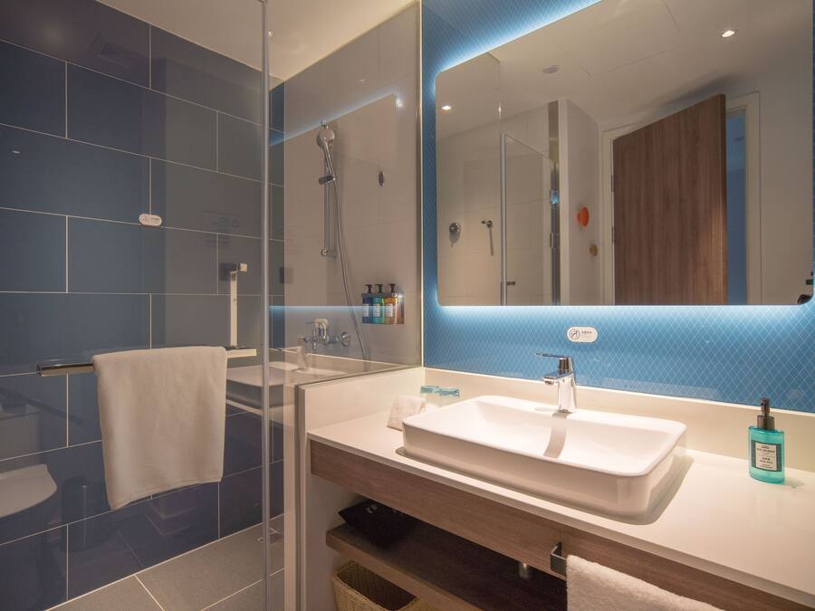 Een moderne badkamer met een douchecabine van glas, een wit wastafelmeubel en een grote spiegel.