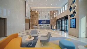 A modern lobby with a reception desk, seating area, and a large digital display.