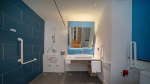 A modern bathroom with blue tiles, a sink, a mirror, and a toilet. - Holiday Inn Express Shanghai Huijin by IHG (Shanghai)