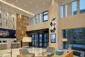 A modern hotel lobby with a reception desk, seating area, and large windows. - Holiday Inn Express Shanghai Huijin by IHG (Shanghai)