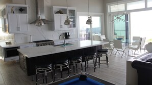 Cocina moderna con una isla grande, taburetes de bar e iluminación colgante.