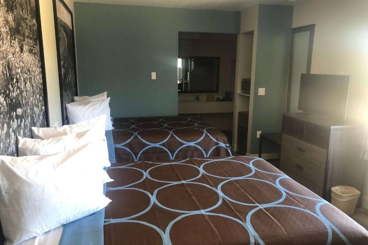 A hotel room with a bed, a dresser, a television, and a bathroom visible in the background.