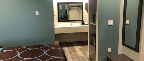 A bedroom with a bed, a vanity with a mirror, and a bench.