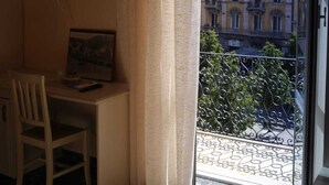 Une pièce comprenant un bureau, une chaise et une fenêtre donnant sur un immeuble.