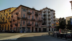 Une vue de rue avec des immeubles à plusieurs étages, une devanture de magasin bien visible avec une enseigne, et des vélos garés.