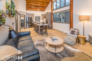 A modern living room with a leather sofa, round coffee table, and a dining area with a kitchen in the background.