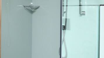 Un baño moderno con cabina de ducha de vidrio, ducha de mano y estante integrado.