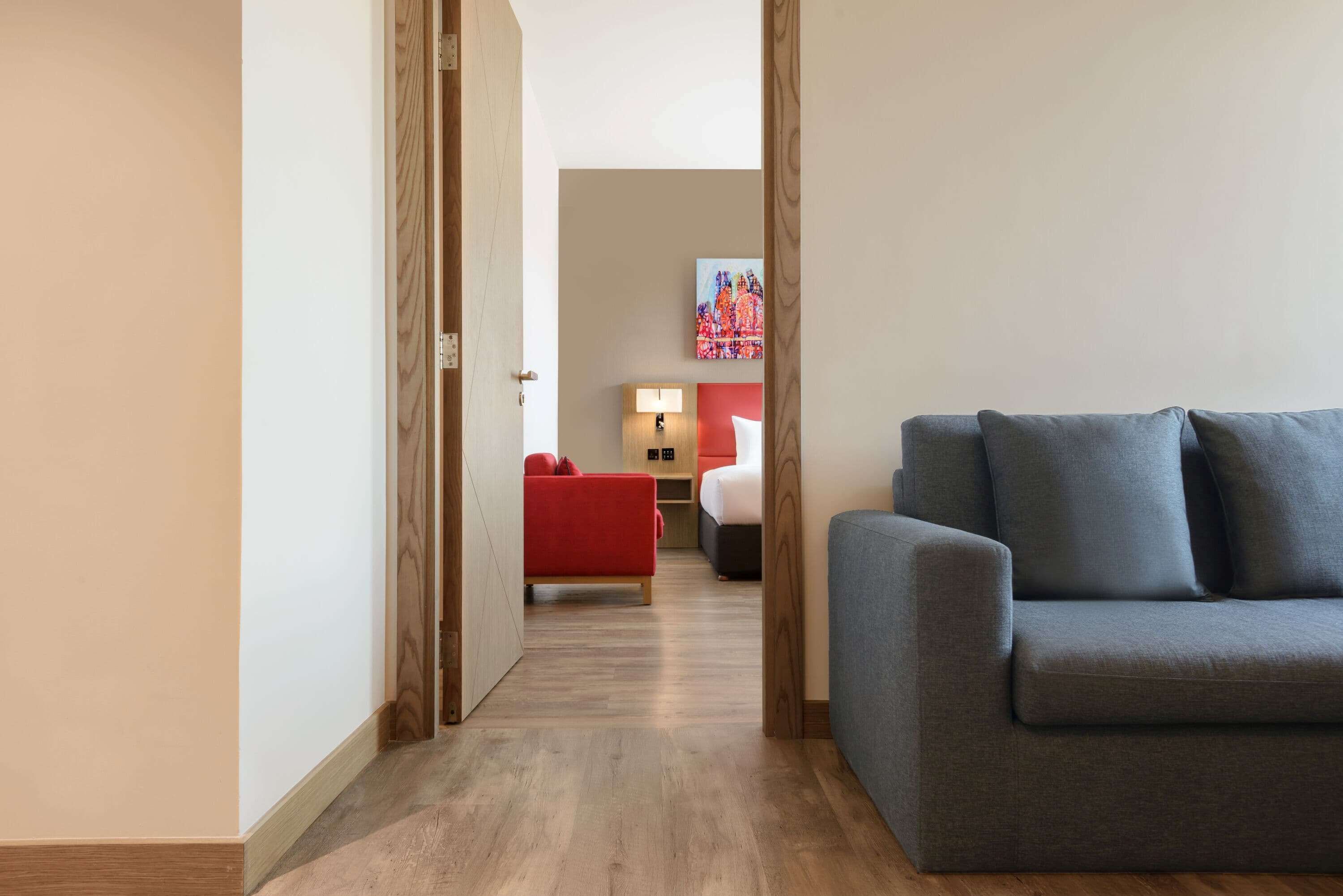 Un pasillo que lleva a una habitación con un sofá rojo y un sofá gris.